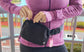 A woman in a purple top showcasing the personal alarm fanny pack
