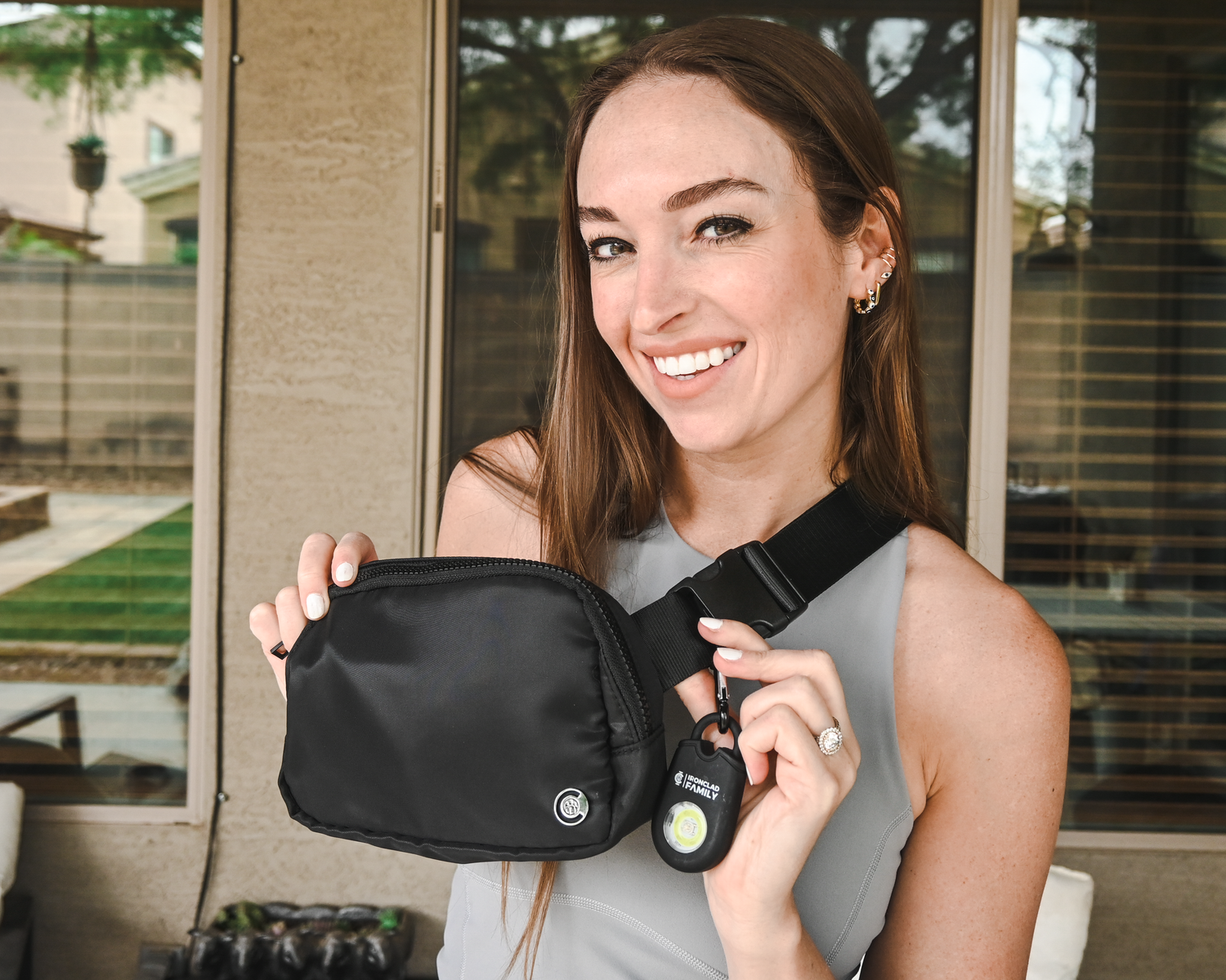 Smiling woman presenting the personal alarm fanny pack