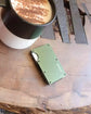 Coffee cup next to the matte metal RFID blocking wallet on a table