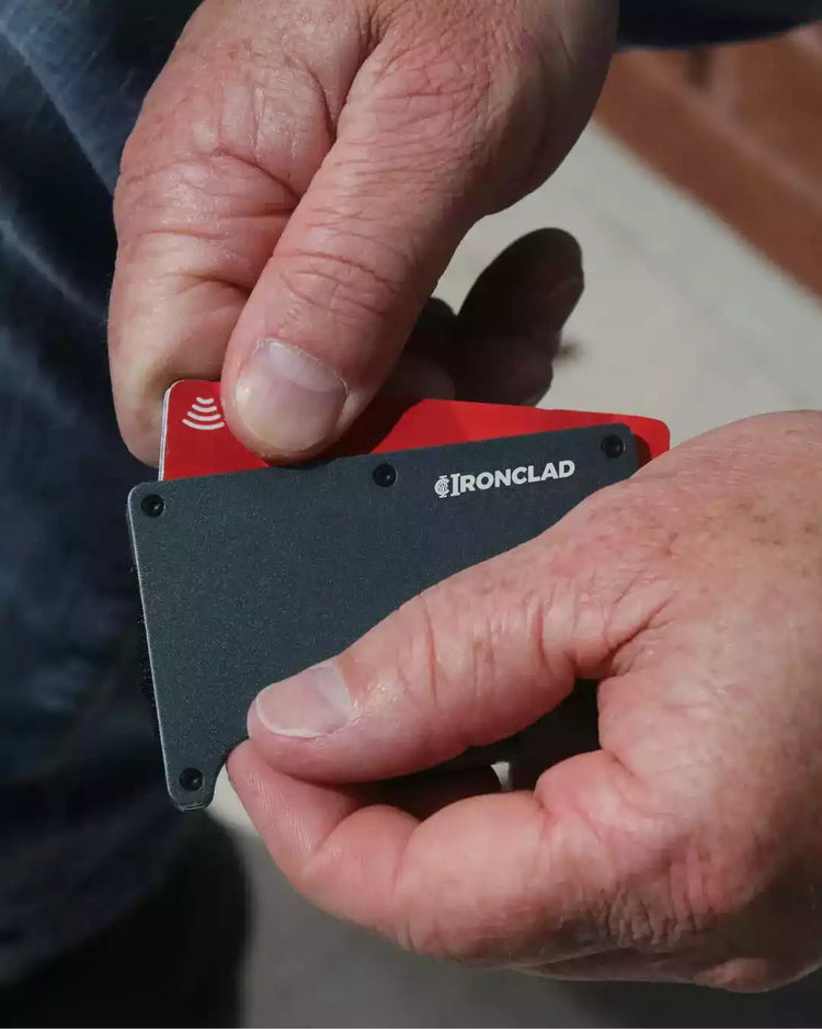 A man holding a Matte Metal RFID Blocking Wallet in red and black