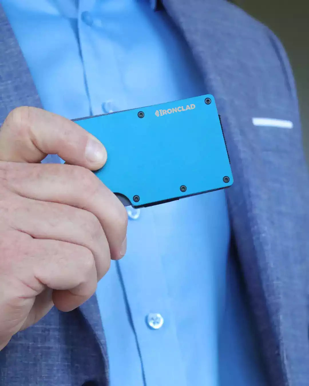 A man in a suit showcasing a blue Matte Metal RFID Blocking Wallet