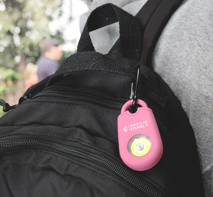 Individual carrying a backpack with a personal alarm sound pendant keychain